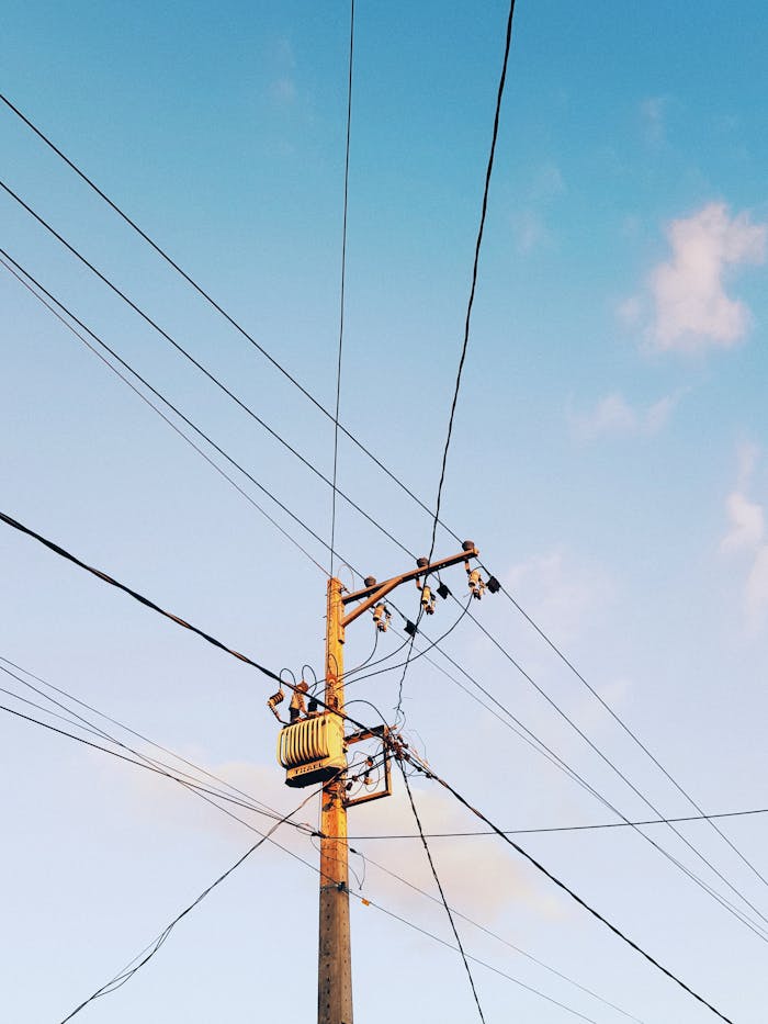 our-story Low-angle shot of electricity poles and wires against a clear blue sky.